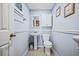 A charming bathroom featuring light blue walls, a pedestal sink, and framed artwork, offering a serene and clean aesthetic at 3626 Lake Joyce Dr, Land O Lakes, FL 34639