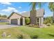 Well-maintained home with a stone chimney, lush landscaping, and an attached garage at 3626 Lake Joyce Dr, Land O Lakes, FL 34639