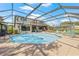 A beautiful in-ground pool surrounded by plenty of patio space and outdoor furniture within a screened enclosure at 3626 Lake Joyce Dr, Land O Lakes, FL 34639
