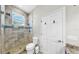 Modern bathroom featuring a tiled shower with glass doors, toilet, and door to the outside at 4604 Blue Marlin Dr, Bradenton, FL 34208