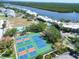 Aerial view of tennis courts, swimming pool, and waterfront condos surrounded by lush greenery at 611 Destiny Dr # 205, Ruskin, FL 33570