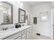 Well-lit bathroom with double vanity, framed mirrors, and a glass-enclosed shower at 6374 Bradford Woods Dr, Zephyrhills, FL 33542