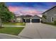 Charming single-story home featuring a stone accent entry and a two-car garage under a vibrant sunset at 6611 Current Dr, Apollo Beach, FL 33572