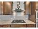Modern cooktop featuring stainless steel range hood and subway tile backsplash at 6611 Current Dr, Apollo Beach, FL 33572