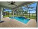 Screened-in pool features a ceiling fan and a jacuzzi overlooking a well-manicured lawn at 6611 Current Dr, Apollo Beach, FL 33572