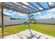 Wide view of the backyard, showcasing the pergola, white fence, and ample green space at 7705 Dragon Fly Loop, Gibsonton, FL 33534