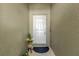 Close-up of a white front door with neutral walls, plants, and a door mat at 7705 Dragon Fly Loop, Gibsonton, FL 33534
