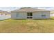 A wide backyard with green grass and a view of the rear exterior with sliding glass doors at 7939 Merchantville Cir, Zephyrhills, FL 33540