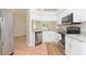 Modern kitchen with white cabinets, stainless steel appliances, and granite countertops is adjacent to the living area at 7939 Merchantville Cir, Zephyrhills, FL 33540