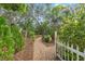 Inviting brick path through a landscaped backyard with lush greenery and a white fence, perfect for relaxation at 9395 Belvedere St, Spring Hill, FL 34608