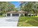 Charming single-story home featuring a well-manicured lawn, double garage, and beautiful mature shade trees at 9395 Belvedere St, Spring Hill, FL 34608