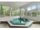 Enclosed sunroom with a green and turquoise hot tub, tiled floors, and white trim at 9395 Belvedere St, Spring Hill, FL 34608