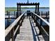 Wooden fishing pier on lake with grill, seating, and lighting for evening enjoyment and relaxation at 10100 Sailwinds N Blvd # 203, Largo, FL 33773