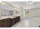 Bright bathroom featuring double vanities, tile flooring, soaking tub, and a separate glass shower at 10712 Pleasant Knoll Dr, Tampa, FL 33647