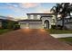 Charming home featuring a three-car garage, a brick driveway, and lush landscaping at 10712 Pleasant Knoll Dr, Tampa, FL 33647
