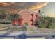 Exterior view of a red brick two-story condo featuring tropical plants, a private entrance, a small balcony, and a beautiful sky at 1095 82Nd N Ter # 1095A, St Petersburg, FL 33702