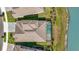 An aerial view of a beautiful tiled roof home with a screened-in pool overlooking a serene lake at 11014 Rustic Timber Loop, San Antonio, FL 33576