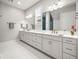 Bright bathroom with double vanity, large mirrors, white cabinetry, and modern fixtures at 11014 Rustic Timber Loop, San Antonio, FL 33576