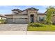 Charming two-story home featuring a stone facade, well-manicured lawn, and a three-car garage at 11014 Rustic Timber Loop, San Antonio, FL 33576