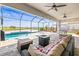 Relaxing outdoor patio area featuring a pool, fire pit, and comfortable seating under a screened enclosure at 11014 Rustic Timber Loop, San Antonio, FL 33576