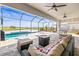 Relaxing outdoor patio area featuring a pool, fire pit, and comfortable seating under a screened enclosure at 11014 Rustic Timber Loop, San Antonio, FL 33576