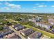 Aerial view of a residential community with townhomes and apartments, lush landscaping, and walking trails under a blue sky at 1103 Coral Ln, Dunedin, FL 34698