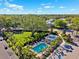 Aerial view of a pool and community area with palm trees, parking, and lush green surroundings on a sunny day at 1103 Coral Ln, Dunedin, FL 34698