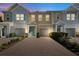 Charming multi-story townhomes at dusk featuring colorful exteriors, attached garages, and a welcoming paver driveway at 1103 Coral Ln, Dunedin, FL 34698