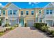Charming multi-story townhomes featuring colorful exteriors, attached garages, and a welcoming paver driveway at 1103 Coral Ln, Dunedin, FL 34698