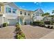 Charming multi-story townhomes featuring colorful exteriors, attached garages, and a welcoming paver driveway at 1103 Coral Ln, Dunedin, FL 34698