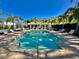 Community pool with lounge chairs, tables, and a pergola, surrounded by palm trees and brick pavers at 1103 Coral Ln, Dunedin, FL 34698