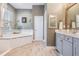 Bright bathroom featuring a soaking tub, wood look tile flooring, and a gray vanity at 13121 Pasture View Loop, Riverview, FL 33579