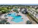 Aerial view of community pool, and splash pad with lake and greenery in the background at 13121 Pasture View Loop, Riverview, FL 33579