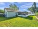 A view of the home's back exterior and screened in porch surrounded by green grass at 13308 Kearney Way, Tampa, FL 33626