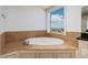 Relaxing soaking tub with window view, surrounded by travertine tile at 13600 Gulf Blvd # 700A, St Petersburg, FL 33708