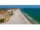 Wide aerial view of beachfront condos featuring a sandy beach, blue ocean water, and blue sky at 13600 Gulf Blvd # 700A, St Petersburg, FL 33708
