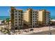 Beautiful exterior view of condos overlooking the beach with open balconies and palm trees at 13600 Gulf Blvd # 700A, St Petersburg, FL 33708