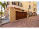 View of private garages with secure wood doors located close to the building with a brick driveway at 13600 Gulf Blvd # 700A, St Petersburg, FL 33708