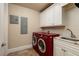 Efficient laundry room equipped with modern, red washer and dryer, sink, and ample storage at 13600 Gulf Blvd # 700A, St Petersburg, FL 33708
