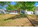 Backyard with a screened in patio and shade provided by mature trees and lush green grass at 1610 Navigator Ln, Tarpon Springs, FL 34689
