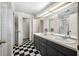 Bathroom featuring double sinks, a large mirror, and a black and white checkered floor at 1610 Navigator Ln, Tarpon Springs, FL 34689