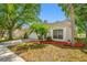Charming home with a manicured lawn, mature shade trees, and a colorful mulch flower bed at 1610 Navigator Ln, Tarpon Springs, FL 34689