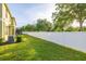 Large, grassy backyard enclosed by a white fence, featuring lush greenery and privacy at 20224 Pond Apple Ln, Tampa, FL 33647