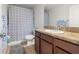 Cozy bathroom with dark wood cabinets, tile floors, and a shower-tub combo with neutral patterned curtain at 20224 Pond Apple Ln, Tampa, FL 33647