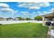 A well-maintained backyard features a white fence, green grass, and a covered patio with outdoor seating at 2800 Flagler Ct, Trinity, FL 34655