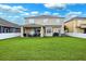 A spacious backyard features a covered patio with seating, a grill, and a lush green lawn at 2800 Flagler Ct, Trinity, FL 34655