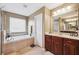 Bright bathroom features a soaking tub, vanity with double sinks, and stylish tile backsplash at 2800 Flagler Ct, Trinity, FL 34655