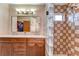 Bathroom featuring double sinks, wood cabinetry, and a tiled shower with glass block divider at 2927 Hickory Grove Dr, Valrico, FL 33596