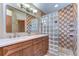 Bathroom featuring double sinks, wood cabinetry, and a tiled shower with glass block wall at 2927 Hickory Grove Dr, Valrico, FL 33596