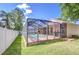 A screened-in pool area is nestled in a grassy yard with a white fence at 2927 Hickory Grove Dr, Valrico, FL 33596